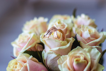 gold wedding rings on a bouquet of white roses