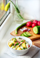 Vegetable vitamin salad with egg, fresh radish cucumber and green onions on a background of chopped vegetables