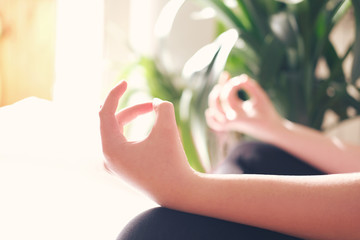 teenage girl or young woman yoga lesson at home during coronavirus pandemic, breathing, meditating, Lotus pose, working out, indoor close up. Well being and mind balance , wellness concept