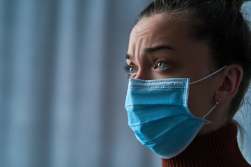 Upset depressed melancholy woman in protective face mask with sad eyes during serious illness,...