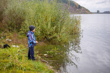 Fototapeta na wymiar fishing kid on the river in autumn