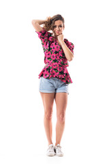Playful fashionable slim sexy young woman in jean shorts holding curly hair looking at camera. Full body isolated on white background. 