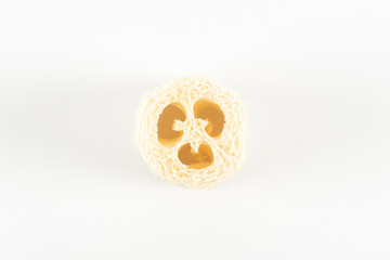 Natural environmental loofah lies on a white background core turned towards us. - obrazy, fototapety, plakaty