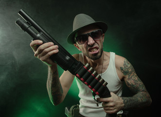 Fototapeta premium an athletic guy with a tattoo poses with a shotgun