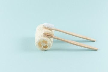 Two toothbrushes lie on a natural environmental loofah, designed for the body, on a white background - obrazy, fototapety, plakaty