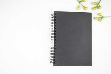 Simple gray colored paper diary and some small flowers before a white background