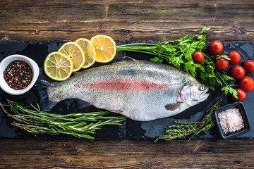 Big fresh salmon with greenery and lemon on the black board