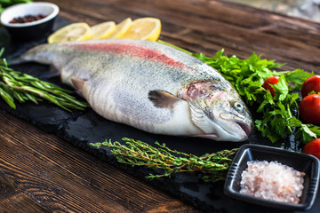 Big fresh salmon with greenery and lemon on the black board