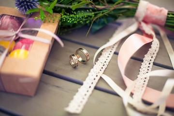 wedding rings on a table with a bouquet of flowers and a box os candies