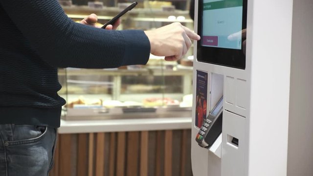 a young man buys a telephone in a contactless way in a self-service machine. men pay by phone. close up. 4k Video 