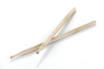 pair of drumsticks on white surface with shadow