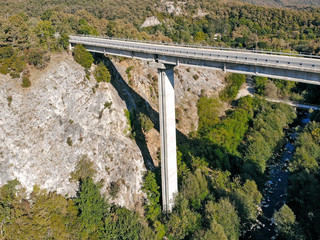 Created by dji camera. An automobile bridge on high pylons through a deep gorge in the mountains.