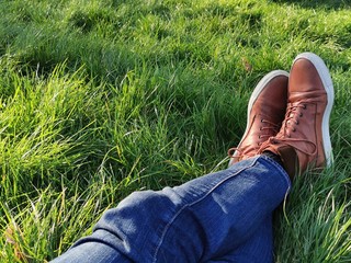 Legs of the man laying on the grass at a sunny day