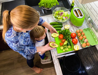  Fair-skinned mom and son prepare food / breakfast in the kitchen in their home.