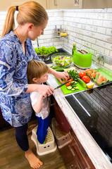  Fair-skinned mom and son prepare food / breakfast in the kitchen in their home.