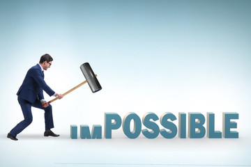 Businessman hitting the word impossible with hammer