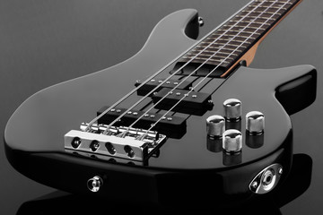 Body of black electric bass guitar on dark background