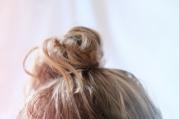 messy bun on the head of a blonde woman. quick hairdo at home because of quarantine. Modern fast hairstyle messy hair. bad hair day concept. 