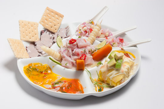 Peruvian food or mix of Peruvian starters: fish cebiche, olive octopus, causa rellena, choritos a la chalaca and fish tiradito served on a white plate