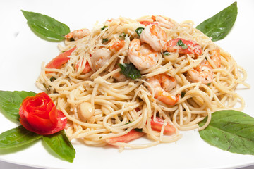 Spaguetti noodles with shrimps and parmesan cheese decorated with basil and cherry tomato, served on a white plate