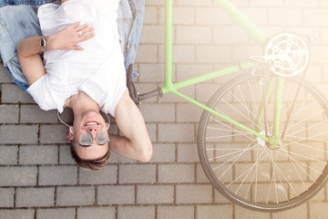 Man lying on the asphalt with bicycle and relax after riding. Active lifestyle. Spring sunny concept.