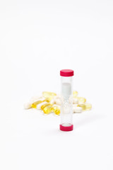 hourglass, vitamins and pills on a white background
