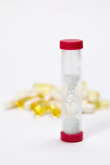 hourglass, vitamins and pills on a white background
