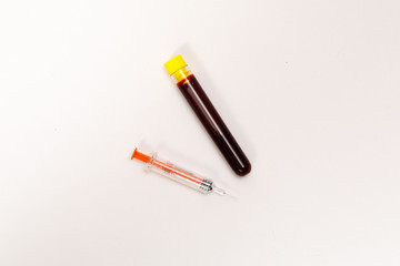 syringe for injection and test tube with blood, pills on a white background