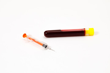 syringe for injection and test tube with blood, pills on a white background