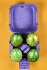 colorful easter eggs in an egg tray on a yellow background