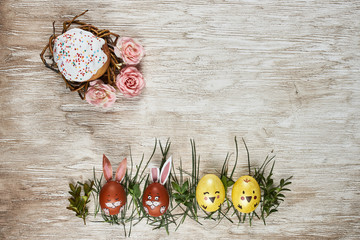 Easter painted eggs and cake on wooden backdrop. Top view.
