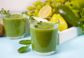 Fresh blended green smoothie in glasses with fruit and vegetables on the background. Health and detox concept.