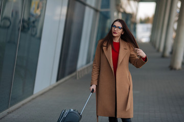 Travel, business trip. People and technology concept - happy young woman with travel bag on city street