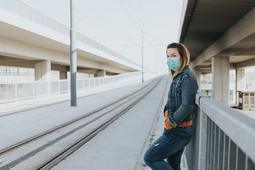 Obraz premium Young woman with a surgical mask in an empty tram station