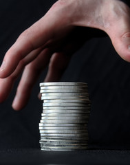 Hand grasping for a stack of silver coins