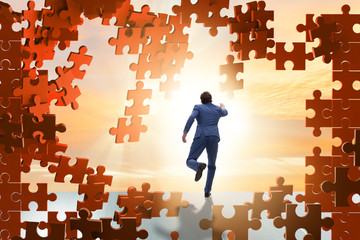 Businessman breaking the wall of jigsaw puzzle