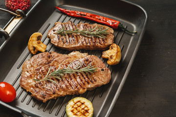Beef steaks with vegetables on grill pan, top view