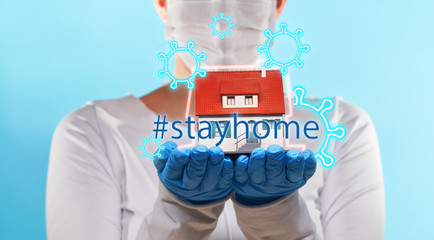 Woman in medical gloves and mask holds house in hands. Concept of home stay, quarantine, security...