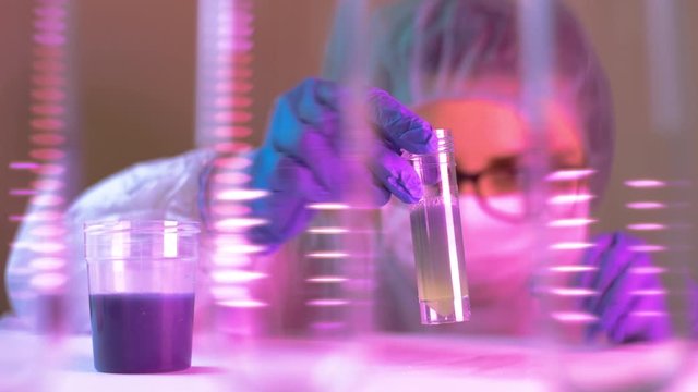 Scientist woman shaking the solvent on  glass tube on lab with other colorful liquid preparations on table searching about Covid-19