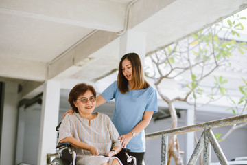 Smiling physiotherapist  taking care of the happy senior patient in wheelchair