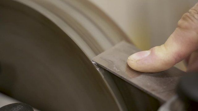 Carpenter sharpening chisel on grindstone