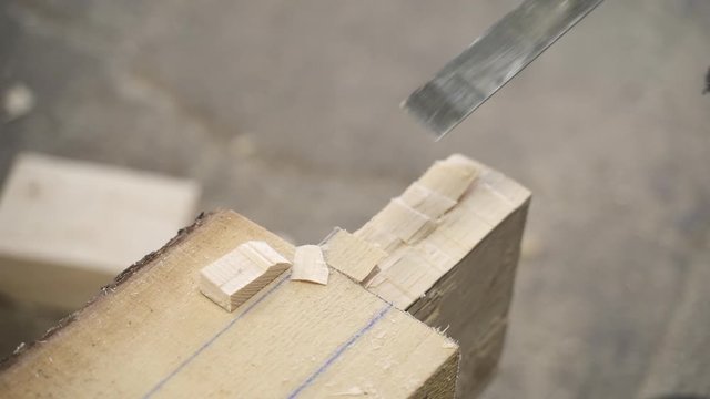 Carpenter cutting wood with chisel