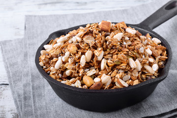 Homemade granola with various nuts and seeds in a cast iron pan