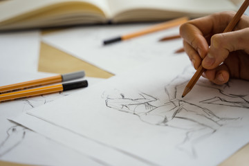 A top view flat lay of many figure drawing pencil and marker sketches. The artist worskspace with male and female drawings and pencils on the white paper, art, craft, creativity, inspiration, concepts