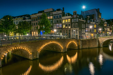 Night Amsterdam cityscape with bridges and houses on a canal.