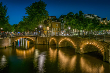Night Amsterdam cityscape with bridges and houses on a canal.