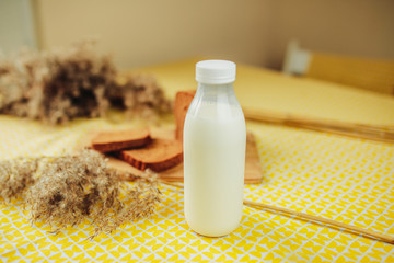 Sliced dark bread and fresh milk bottle on yellow table. Healthy nutrition, healthy food on the table. White milk bottle and fresh bread.