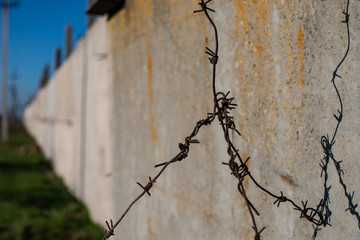 A barbed roof with a large piece, against the background of an old concrete fence. restricted area