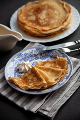 A stack of thin pancakes on a plate. Homemade pastries. Pancakes for breakfast. Appetizing food. Thin pancakes on a plate. Homemade crepes, tasty food. Staple of yeast pancakes.