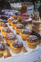 Cup cake, pastelillo o panqué con cubierta de chocolate en mesa de dulces